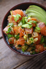 Poke bowl with raw marinated salmon, cucumbers and avocado. Macro shot
