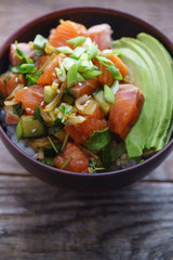 Poke bowl with raw marinated salmon, cucumbers and avocado. Macro shot