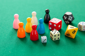 Colored game figures chips for board games. Collection of dice cubes on green table