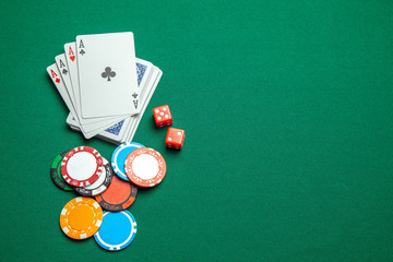Concept of gambling in casino, sports poker. Game cards with dice and colored chips sleep green game table. Copy space for text.