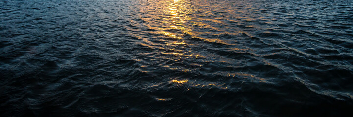 Water waves and orange sun light reflection