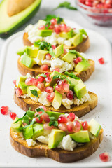 Avocado feta cheese pomegranate seeds crostini. Selective focus, space for text.