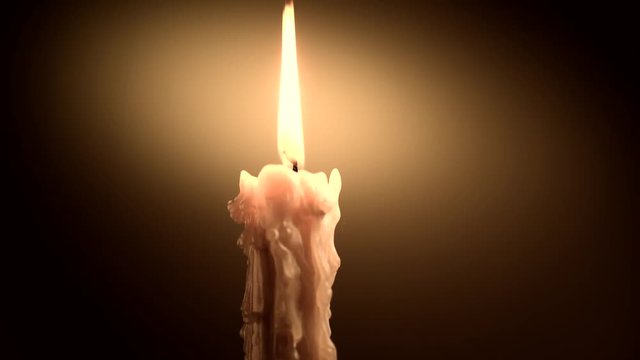 Candle flame closeup on dark background. Candle light border design. Melted wax candle burning at night. Rotation. 3840X2160 4K UHD video footage