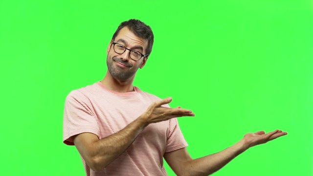 man extending hands to the side and inviting to come  on green screen chroma key background