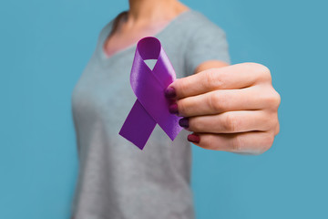 Elderly woman holding purple ribbon awareness w copy space. Symbol is used to raise awareness for Alzheimer's disease, elder abuse, epilepsy, pancreatic cancer, thyroid cancer and lupus. Close up.