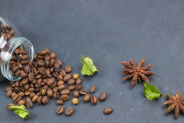 roasted coffee beans poured from a glass jar. angular placement of the coffee object. on dark concrete. horizontal view. copy space