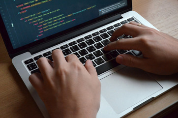 Male hands on a black keyboard. European coding on a computer. Side view.