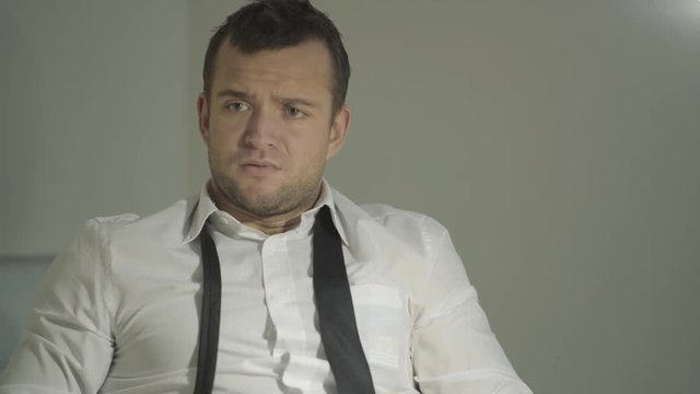 The guy detective in a white shirt listens to the interlocutor with a surprised face in his office