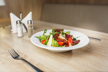 Carpaccio plates ready to serve on the table. Carpaccio in a white bowl on a wooden table. Middle plan.