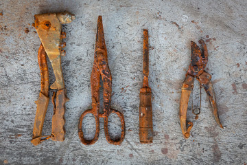 A set of rusty craftsman tools placed on a weathered concrete floor, top view
