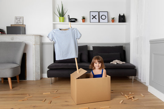 Little girl playing pretend in a cardboard box