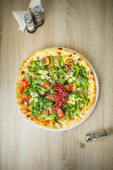 Spicy pizza with beef, green pepper, olives and onion on cutting board. Close up