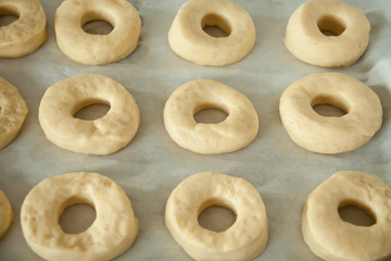 Raw donuts on the baking paper and tray. Cooking process.