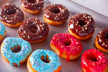 Fresh colorful chocolate donuts on the baking tray
