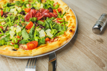 Spicy pizza with beef, green pepper, olives and onion on cutting board. Close up