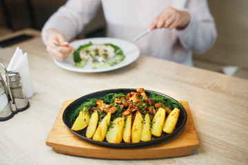 Fried potato with mushrooms chanterelle. beautifully rustic in a black plate rustic on a wooden table.