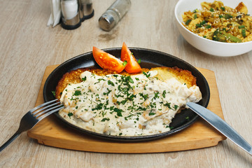 Plate with tasty potato pancakes with tomatoes and gravy on wooden table