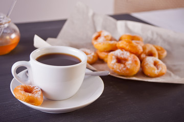Fresh mini donuts with cup of coffee on the wooden table