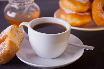 Fresh donuts with cup of coffee on the wooden table