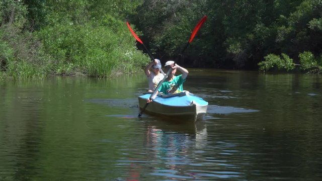 A boy and a girl in a canoe floating on the river. They are traveling and happy.