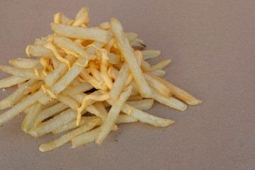 Unhealthy junk food, group of cheesy french fries on brown paper with blank space, fast food concept