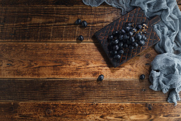 Dark sweet grapes on decorative board on wooden background.