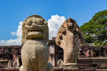 Close up of old lion sculpture and old snake sculpture at the historic site in Thailand with blue sky and cloud background. 