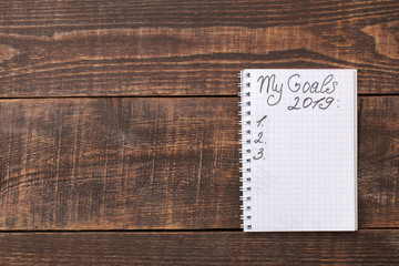 Goals for 2019. text in notebook. on a brown wooden background. with space for text.