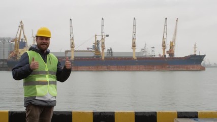 seaport worker with a beard and a helmet makes like