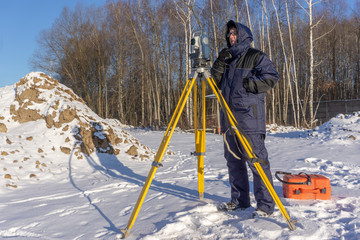 Surveyor conducts surveying in winter at a construction site
