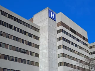 Fotobehang Large concrete building with  H sign for hospital © Spiroview Inc.
