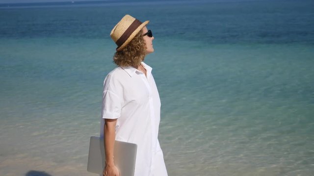 Young Business Woman Walking On The Beach With Laptop