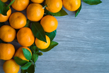 Orange sweet tangerines with green leaves on wooden background.