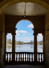 A view of a placid lake through the columns of a temple summerhouse