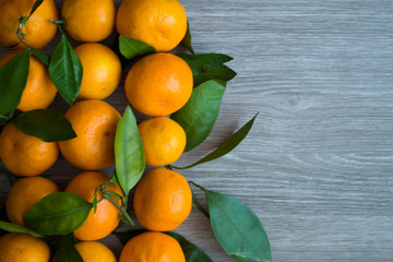 Orange tangerines with green leaves on wooden background.