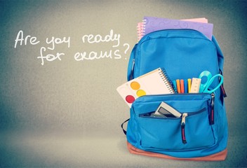 Colorful school supplies in backpack on wooden background