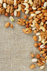 Mix of nuts lying on a background of brown cloth burlap.