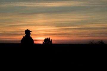 Fototapeta na wymiar man admiring red autumn sunset in the field, silhouette of man and tree