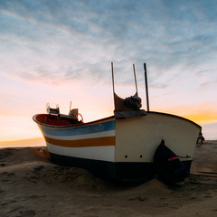 Traditional wooden fishing boat on sand at Caparica beach, near Lisbon, Portugal