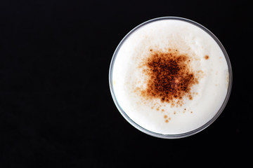 Ice cappuccino in plastic cup. Top view of milk foam and cinnamon powder topping. Refreshment beverage.