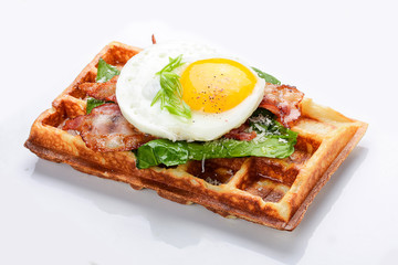 Belgian waffle on a white background. Stuffed with bacon, eggs and salad.