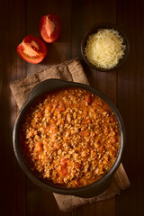 Homemade bolognese sauce made of fresh tomatoes, onion, carrot, garlic and mincemeat, served in rustic bowl, photographed overhead with natural light (Selective Focus on the top of the sauce)