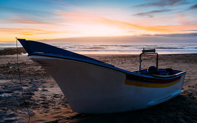 Traditional wooden fishing boat on sand at Caparica beach, near Lisbon, Portugal