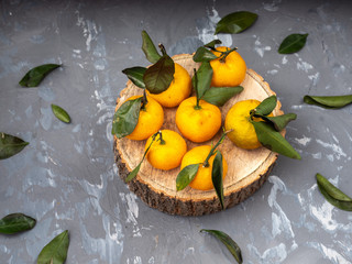 tangerines with leaves on a wooden disk, top view