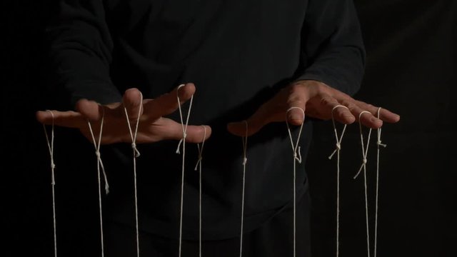 Hands of a puppet master working the strings