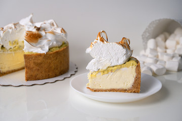 Lemon meringue cheesecake on white plate on white background