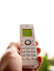 Man hand holding outdoor home office white cordless phone dialing a number on the white keyboard try to reach signal