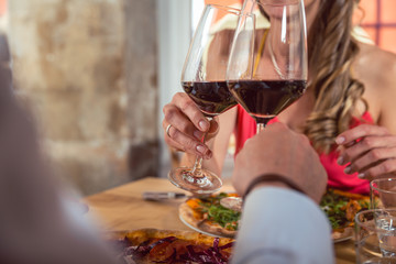 Close-up of couple at restaurant toasting with glasses of red wine