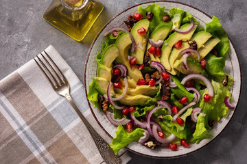 Healthy salad with avocado, pomegranate seeds and walnuts.