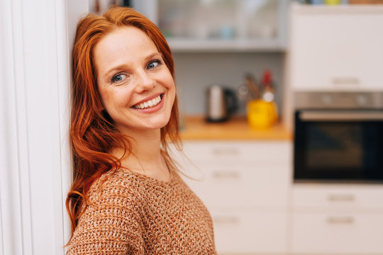 Happy, smiling, young redhead woman at home